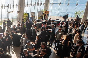 Group of people in an event space with lots of windows facing the Lake Ontario