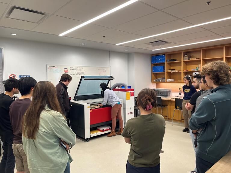 People standing around the Trotec laser cutter leaning how to use it. 