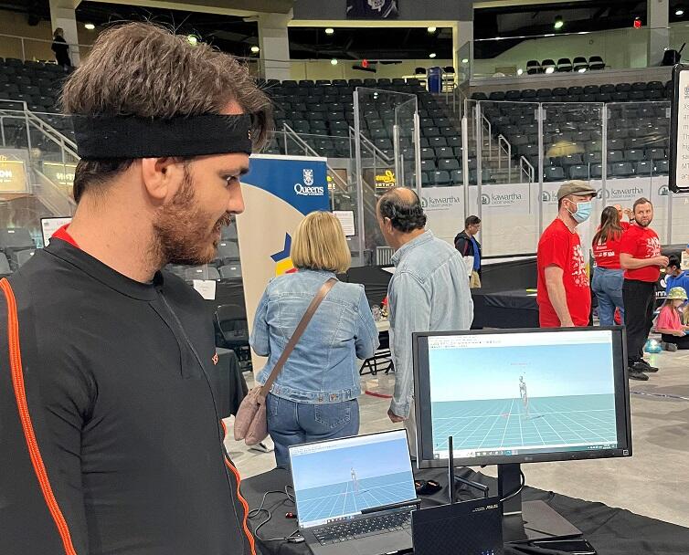 Man wearing a Xsens motion capture suit looking at himself on a computer