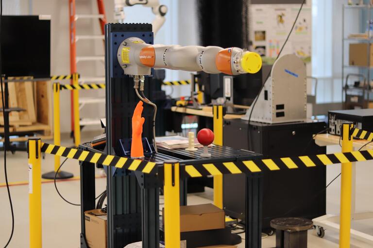 Kuka iiwa robot arm surrounded by caution stands.
