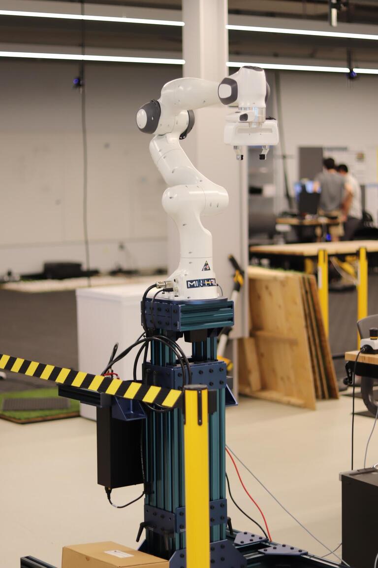 Franka Emika Panda robot arm mounted on a blue stand.