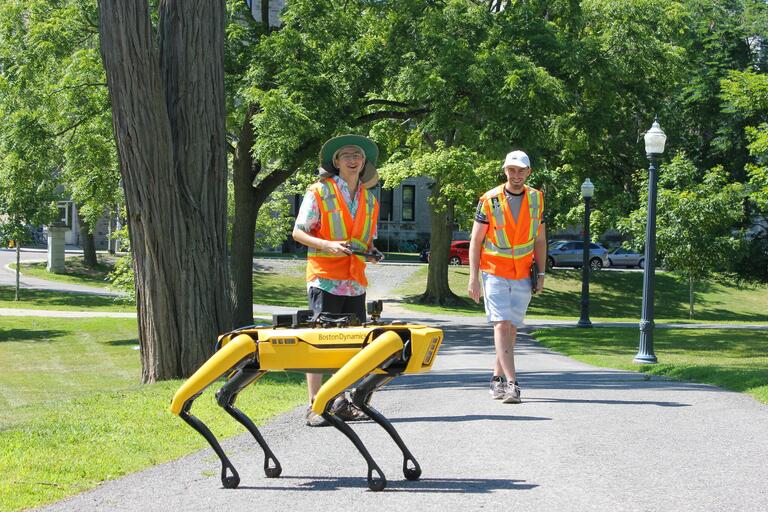 Boston Dynamics Spot quadruped robot with two students outdoors in a park