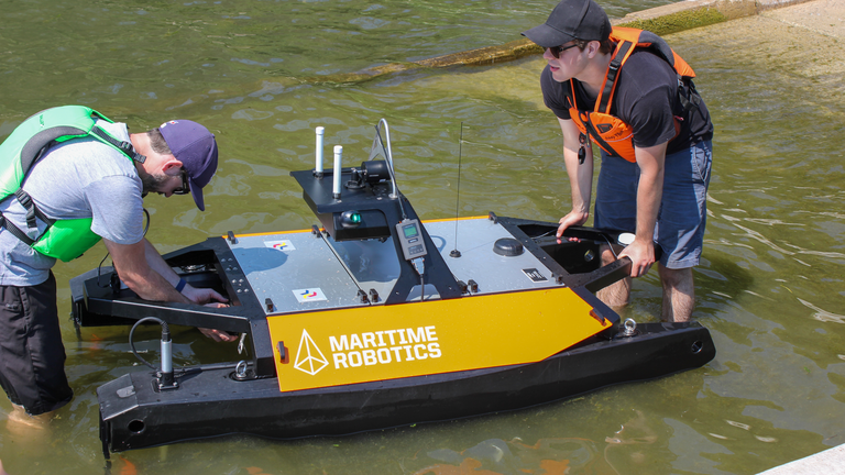 Small marine USV,  with two researchers launching the boat in the water. 
