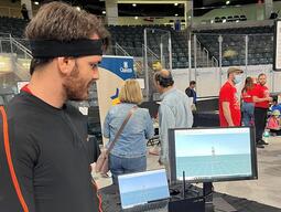 Man wearing a Xsens motion capture suit looking at himself on a computer