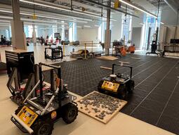 Open research space with a black tiled floor. Featuring two Husky Robots