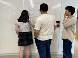 Three students writing on a whiteboard