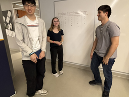 Three students standing in front of a whiteboard