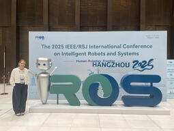 Nia Ralston standing next to the IROS 2025 sign in Hangzhou, China