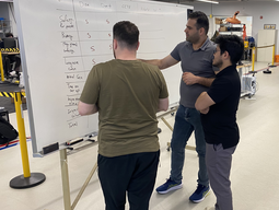 Three students writing on a whiteboard