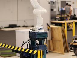 Franka Emika Panda robot arm mounted on a blue stand.