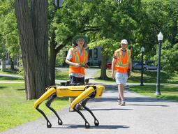 Boston Dynamics Spot quadruped robot with two students outdoors in a park