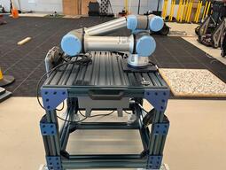 UR5e robot arm on a blue stand.