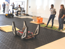 Two students standing next to the Ibex robot, the robot has tracks for wheels.