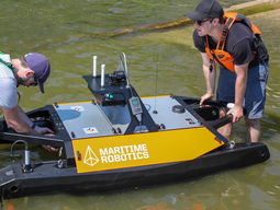 Small marine USV, with two researchers launching the boat in the water.
