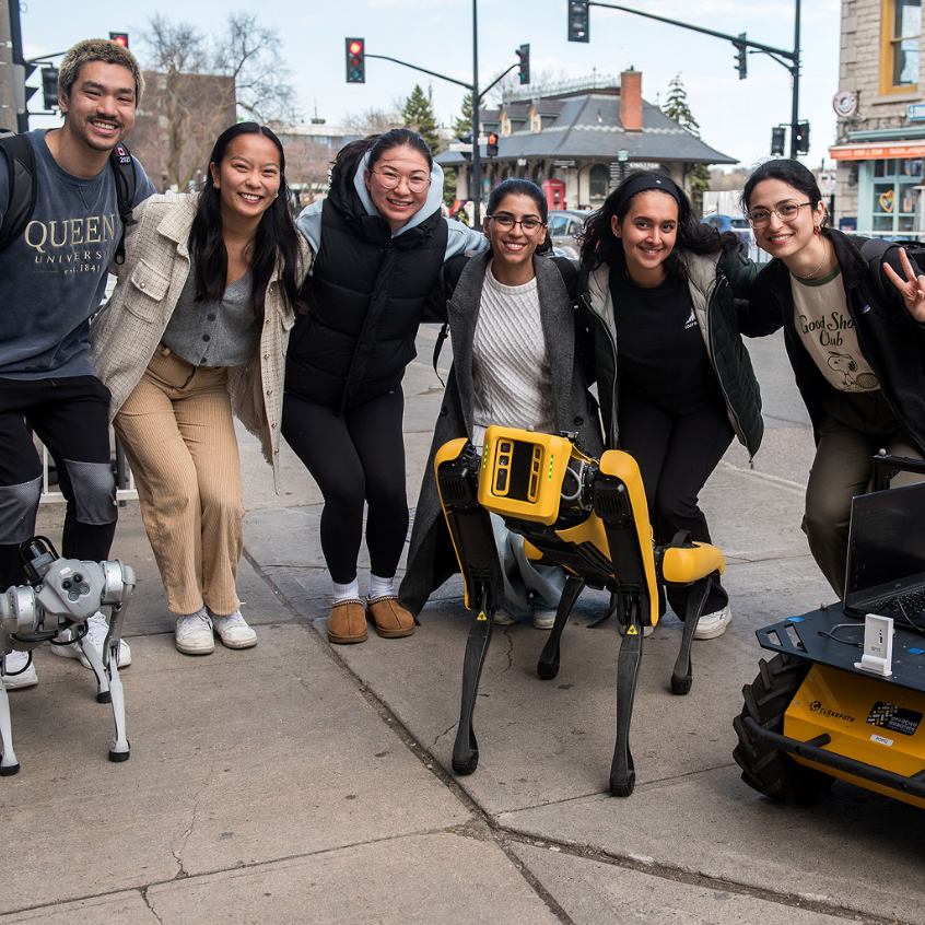 Group of students posing with mobile robot dogs